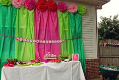 a table with food on it in front of a green and pink curtained wall