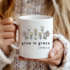 a woman holding a coffee mug with flowers on it that says, grow in grace