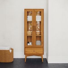 a wooden cabinet sitting next to a basket on top of a floor in a room