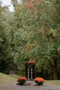 an outdoor ceremony set up in the middle of a wooded area with orange flowers and greenery