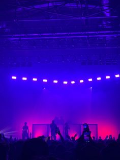 people standing on stage with their hands up in front of the audience at a concert