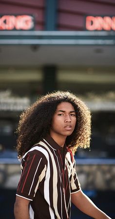 a man with an afro standing in front of a diner