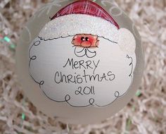 a white ornament with a santa clause on it's face and writing merry christmas 2011