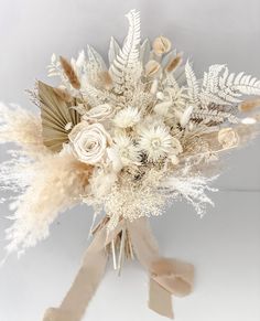 a bridal bouquet with feathers and flowers in it on a white tablecloth background