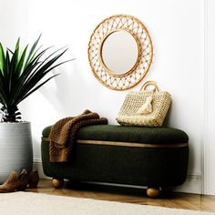 a living room with a green couch, potted plant and round mirror on the wall