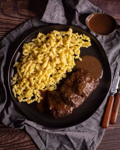 macaroni and meat with gravy on a plate next to a fork