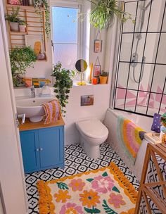 a bathroom with a sink, toilet and bathtub covered in colorful rugs next to a window