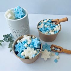 two bowls filled with blue and white candies next to a cup full of marshmallows