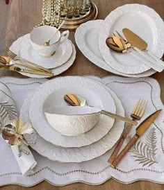 the table is set with white dishes and gold cutlery, along with silverware