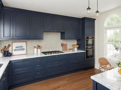 a kitchen with dark blue cabinets and white counter tops, an island in the middle