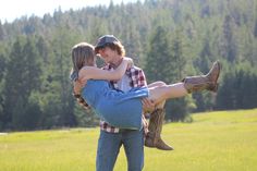 a man carrying a woman on his back in the middle of a field with trees behind him