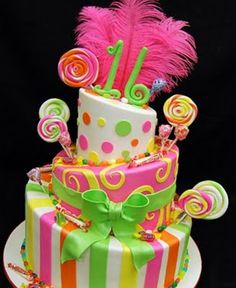 a multi - tiered cake decorated with candy, lollipops and feathers