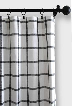 a black and white checkered curtain hanging from a metal rod with two hooks on it