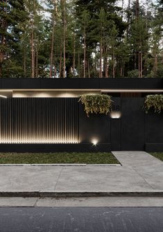 a modern house in the middle of a forest with lights on it's side