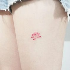 a woman's thigh with a small pink flower tattoo on her left side leg