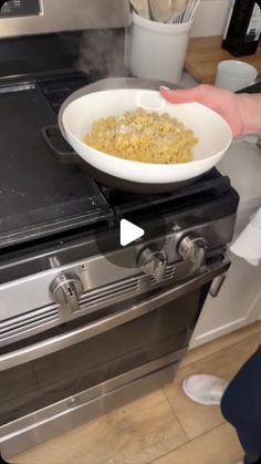 a person holding a bowl of food in front of an oven