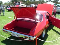 an old red car with its hood open on display at a car and truck show