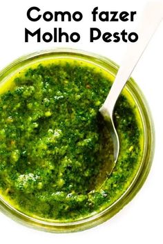 a bowl filled with green pesto next to a spoon