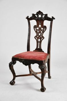 an antique wooden chair with red upholstered seat and back cushion, on a white background