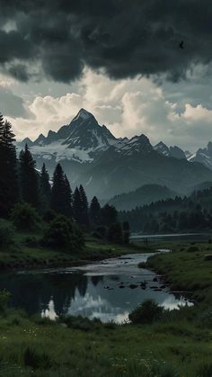 the mountains are covered in dark clouds and green grass, with a small stream running between them