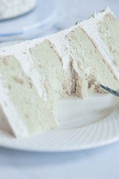 a piece of white cake on a plate with a fork in it and another slice missing