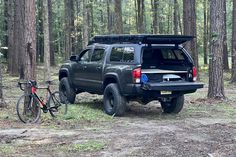 a truck parked in the woods next to a bike