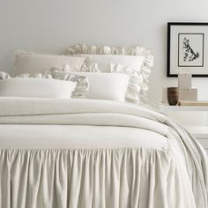 a white bed with ruffled sheets and pillows