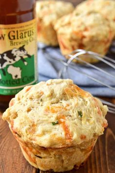 two muffins sitting on top of a wooden table next to a bottle of beer