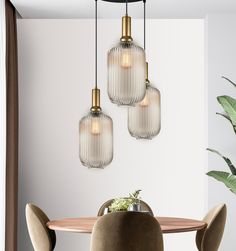 three glass pendant lights hanging over a dining room table