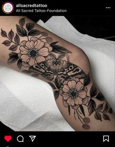 a black and white photo of a moth on a flowered arm with flowers in the background