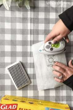 a person is using an electric iron on top of a piece of paper next to other items