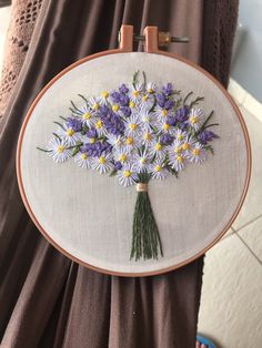 a person holding up a cross - stitch embroidery kit with flowers on it