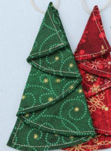 three christmas tree ornaments hanging from strings on a white surface with green, red and gold designs