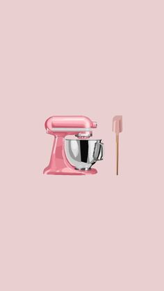 a pink mixer with a wooden spatula next to it on a pink background,