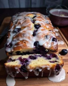 a loaf of blueberry bread sitting on top of a wooden cutting board