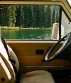 there is a view from the inside of a car looking out at water and trees