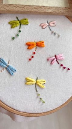 a close up of a embroidery on a wooden frame with dragonflys and flowers