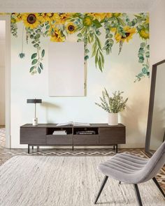 a living room with sunflowers painted on the wall and a gray chair in front of it