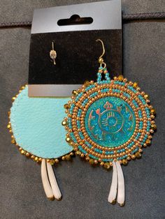 a pair of earrings with beads and tassels hanging from it's packaging