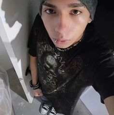 a young man wearing a black t - shirt and green beanie poses for the camera