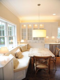 a kitchen with white cabinets and a table in the center, along with two chairs