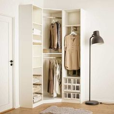 an open closet with clothes on hangers, and a lamp in the corner next to it