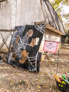 a wooden structure with spider webs painted on it and a sign next to it