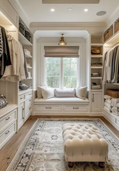 a walk - in closet with white cabinets and drawers, a bench on the floor