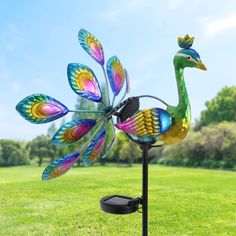 a colorful bird wind spinner sitting on top of a green field