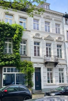 an apartment building with vines growing on it's side and cars parked in front