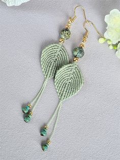 the earrings are made with green beads and tassels, along with white flowers