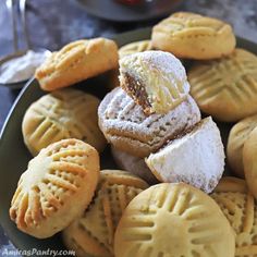 some cookies are sitting on a plate with powdered sugar and jelly in the middle