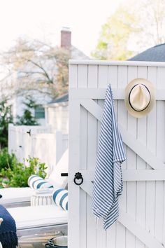 a hat is hanging on the side of a white shed with blue and white striped towels