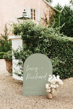 a sign that says lacy richard on it next to some flowers and bushes in front of a building